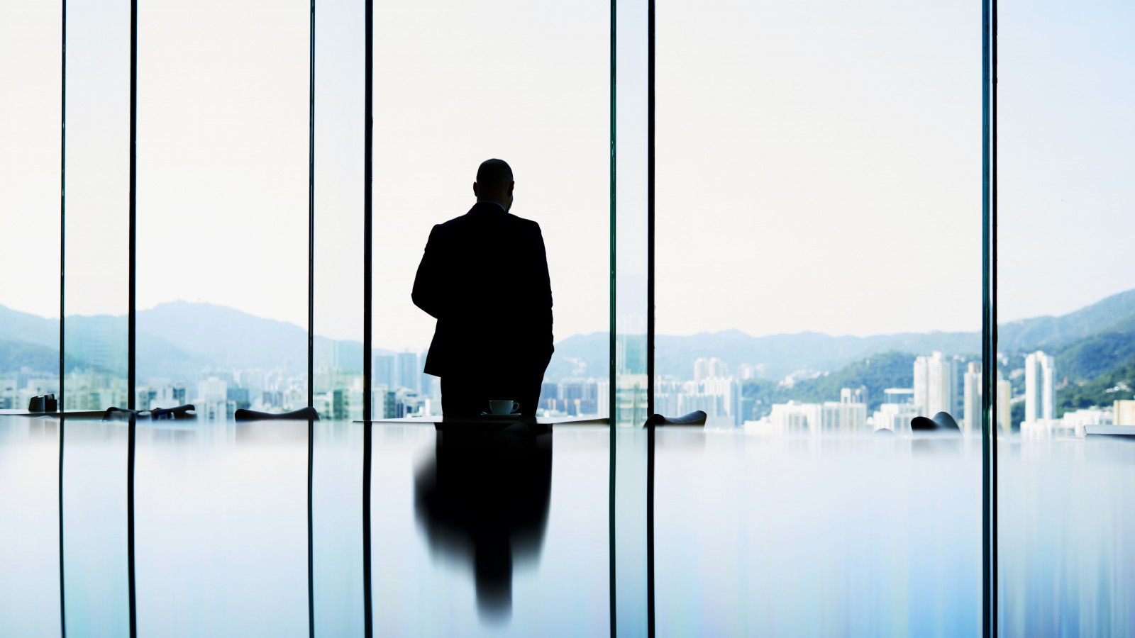 Silhouette eines Mannes vor offener Fensterfront einer Chefetage.