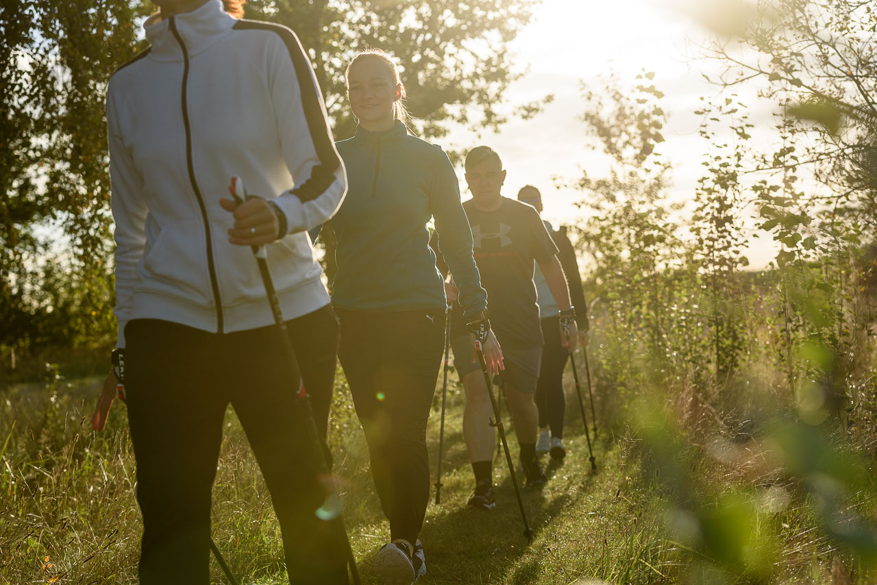 Patienten betreiben in der Sport- und Bewegungstherapie Nordic Walking in der Natur