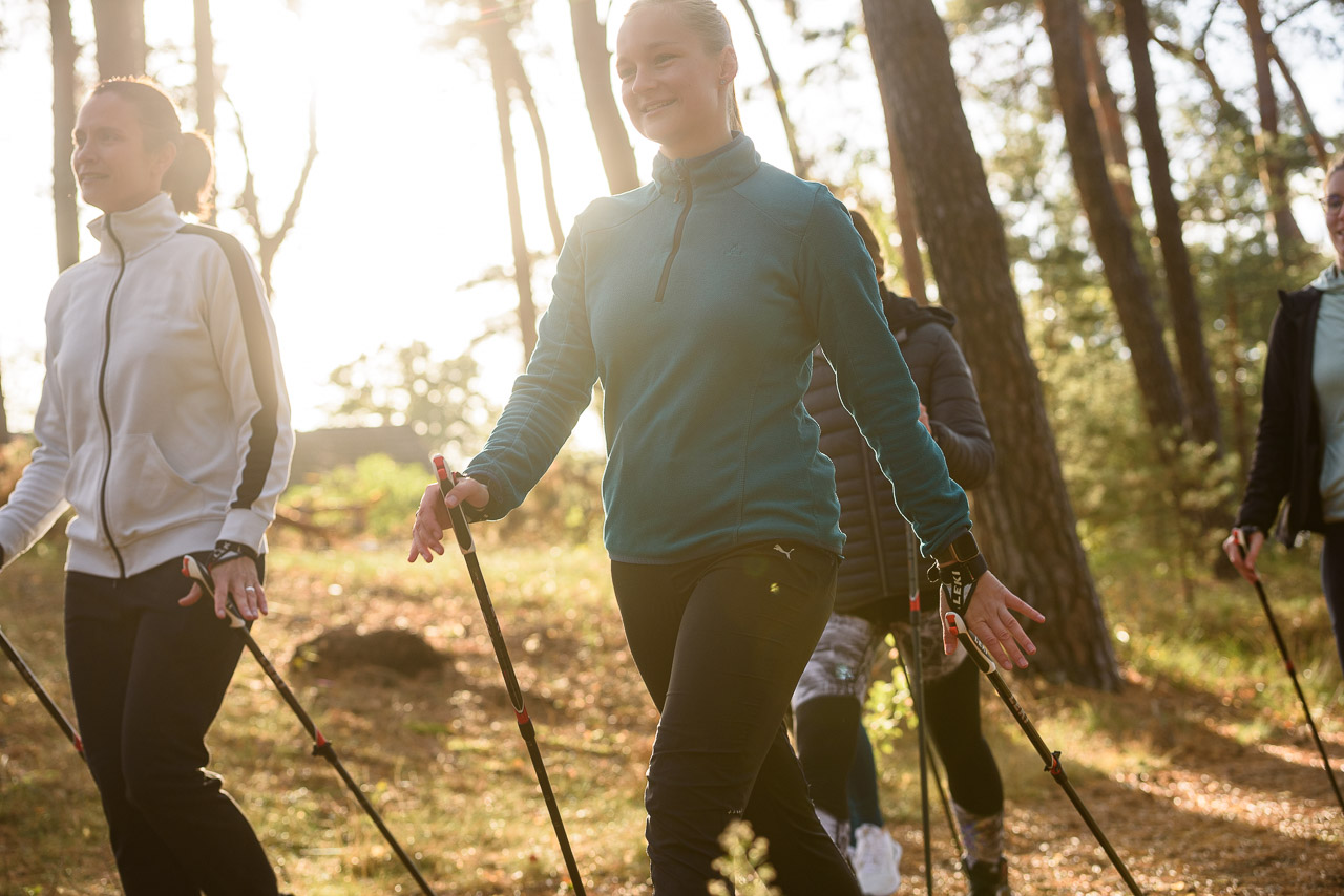 Patienten betreiben in der Sport- und Bewegungstherapie Nordic Walking in der Natur