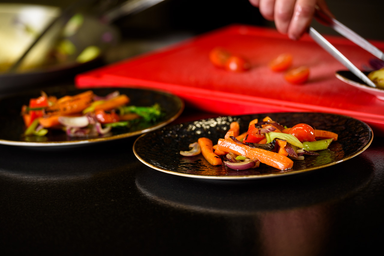 Frisch gekochtes Gemüse wird auf edlem schwarzen Teller angerichtet